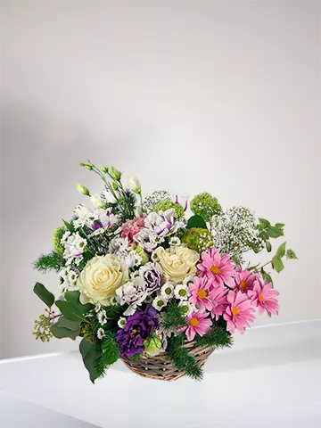 Cestino in vimini con rose bianche margherite rosa e lisianthus bianco viola